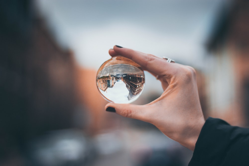 Selektive Fokusfotografie einer Frau, die eine klare Glaskugel hält