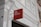 A red rectangular sign with the words 'we are social' is affixed to the exterior of a white building. The building features architectural elements such as window shutters and decorative molding, with visible piping attached to the wall.