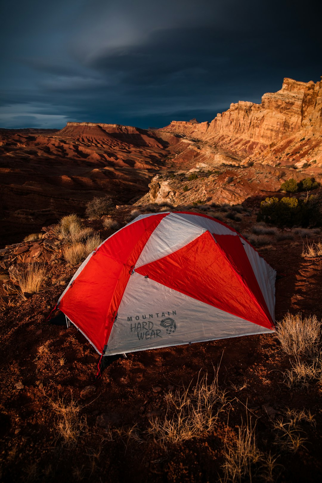 red and white Mountain Hard Wear tent on ground beside rock formation
