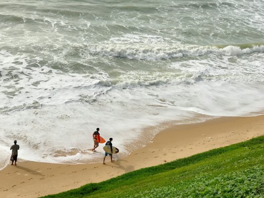Two surfers walking out across the sand — Natal, Brazil