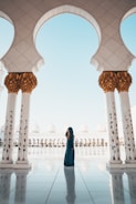 woman standing on white tiled floor in the middle of concrete pillars