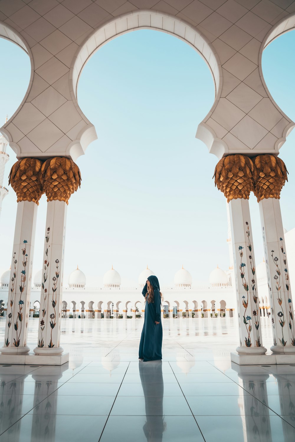 woman standing on white tiled floor in the middle of concrete pillars