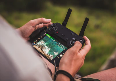 Close-up of a drone controller with farmland in the background.
