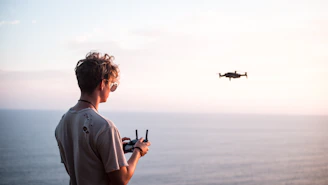 man using quadcopter drone near sea during daytime