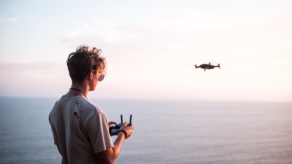 man using quadcopter drone near sea during daytime