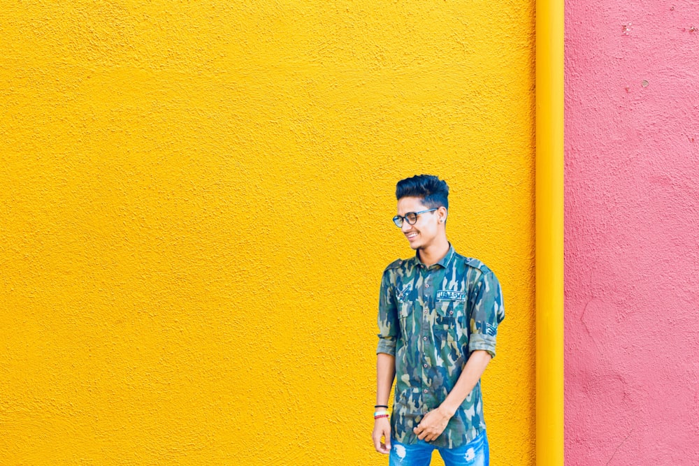 smiling man standing near yellow and pink wall