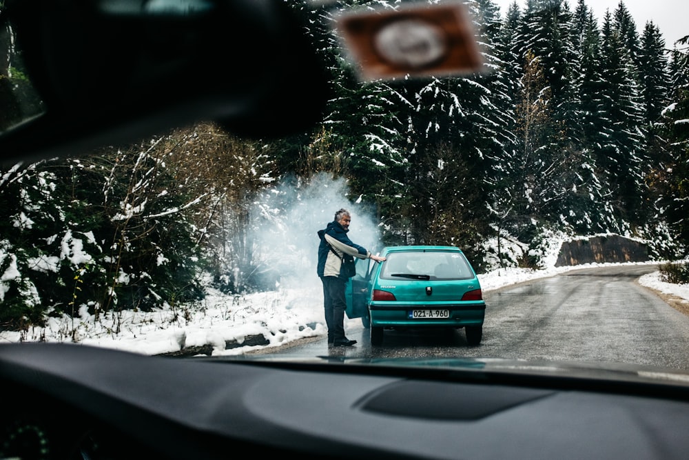 homme debout devant le hayon d’un véhicule turquoise