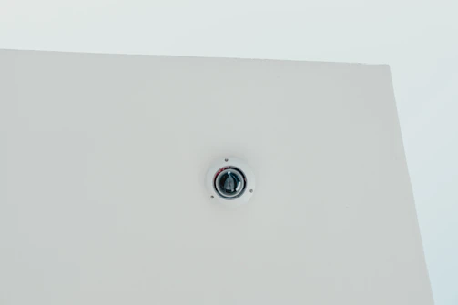 Minimalist dome camera installed on a white ceiling with soft natural light