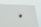 A security camera is mounted on a flat white ceiling, centrally positioned, with a minimalist and clean appearance.