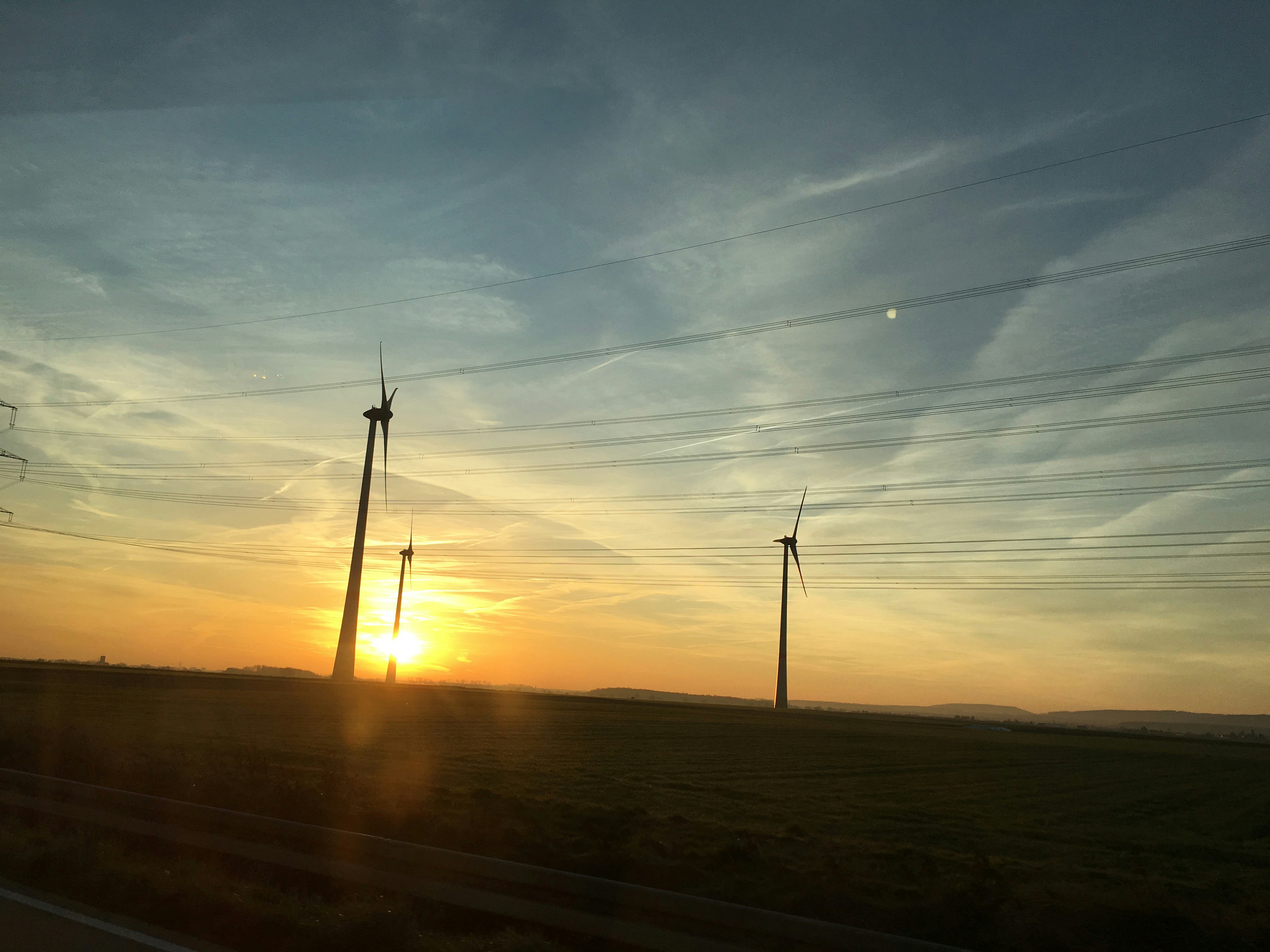 Wind turbines in green field at golden hour, clean energy, sustainability, bright sky background