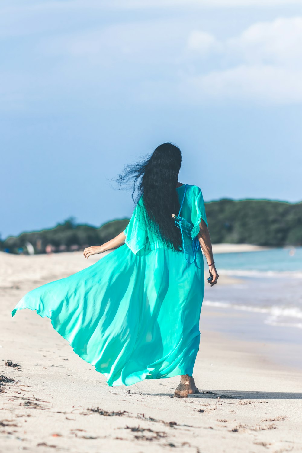 woman in blue short-sleeved dress waling beside body of water
