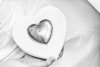 A gentle hand holding a small, glowing heart against a soft, muted background.