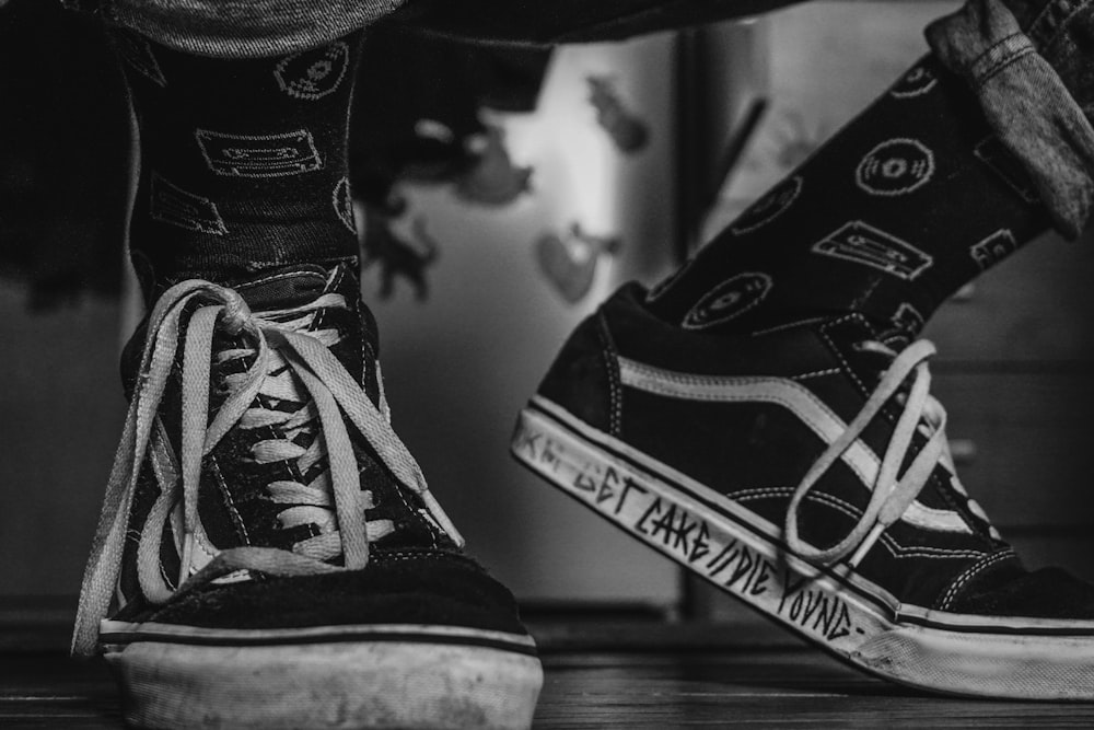 grayscale photo of person wearing Vans low-top sneakers