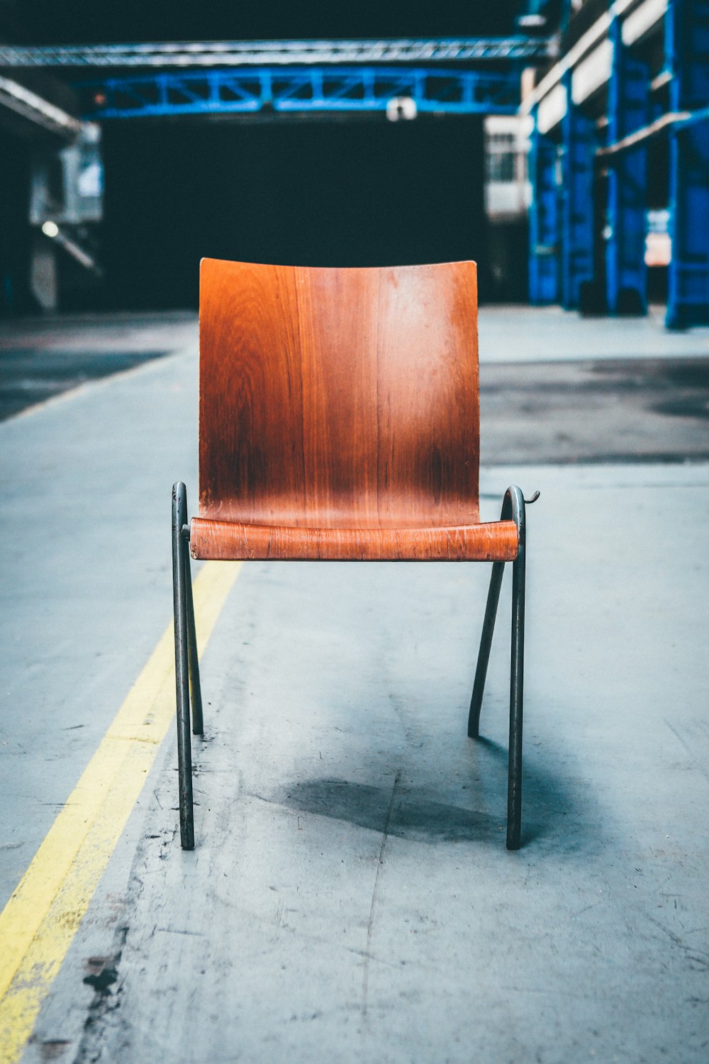 灰色の舗道に黒い金属のベースを持つ茶色の木製椅子