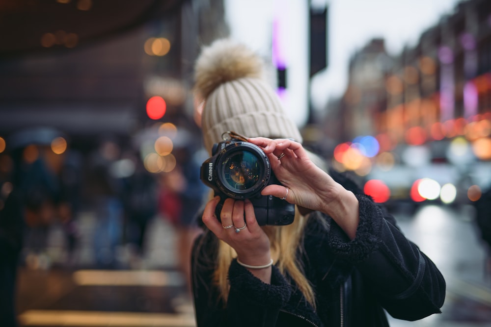 mujer sosteniendo una cámara Canon DSLR