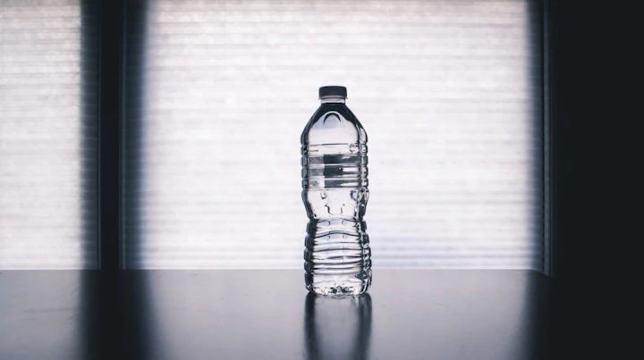 A clear glass of warm water with fresh lemon slices on a wooden surface