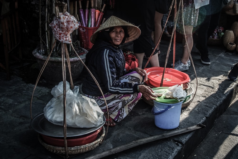 woman sitting beside street bucket