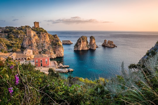 photo of house near cliff and body of water in Tonnara di Scopello Italy