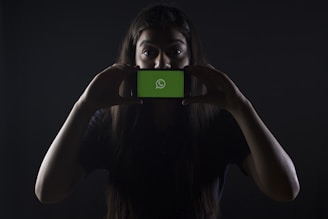 woman holding black smartphone at Whatsapp logo