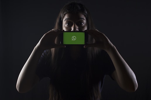 woman holding black smartphone at Whatsapp logo