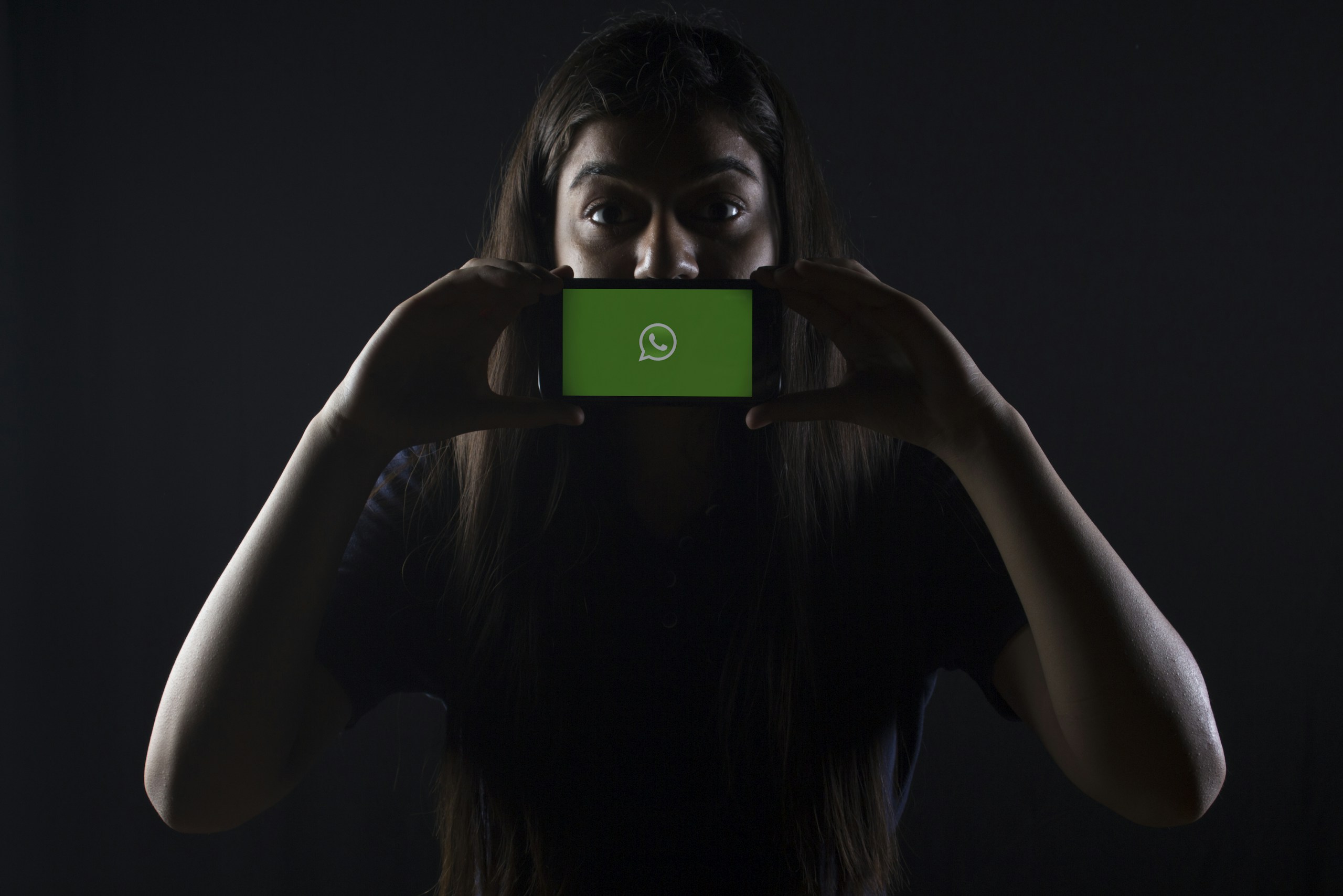 woman holding black smartphone at Whatsapp logo