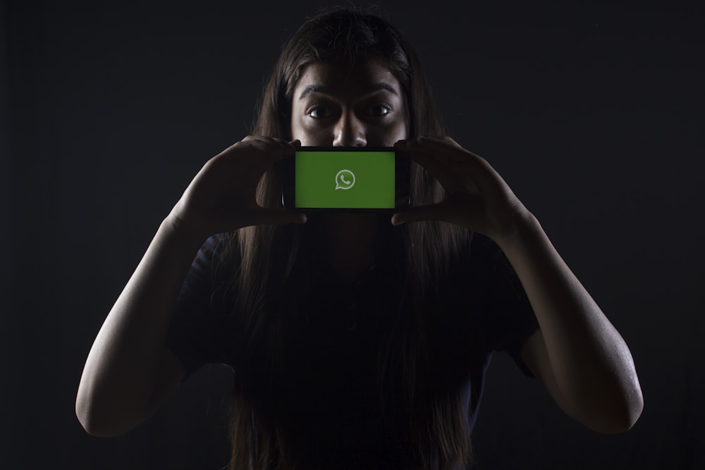 donna che tiene lo smartphone nero al logo di Whatsapp