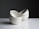 Four white ceramic bowls are neatly stacked in an asymmetrical arrangement on a glossy white surface. The background is a smooth, dark gradient, creating a contrast with the simplicity and elegance of the bowls.