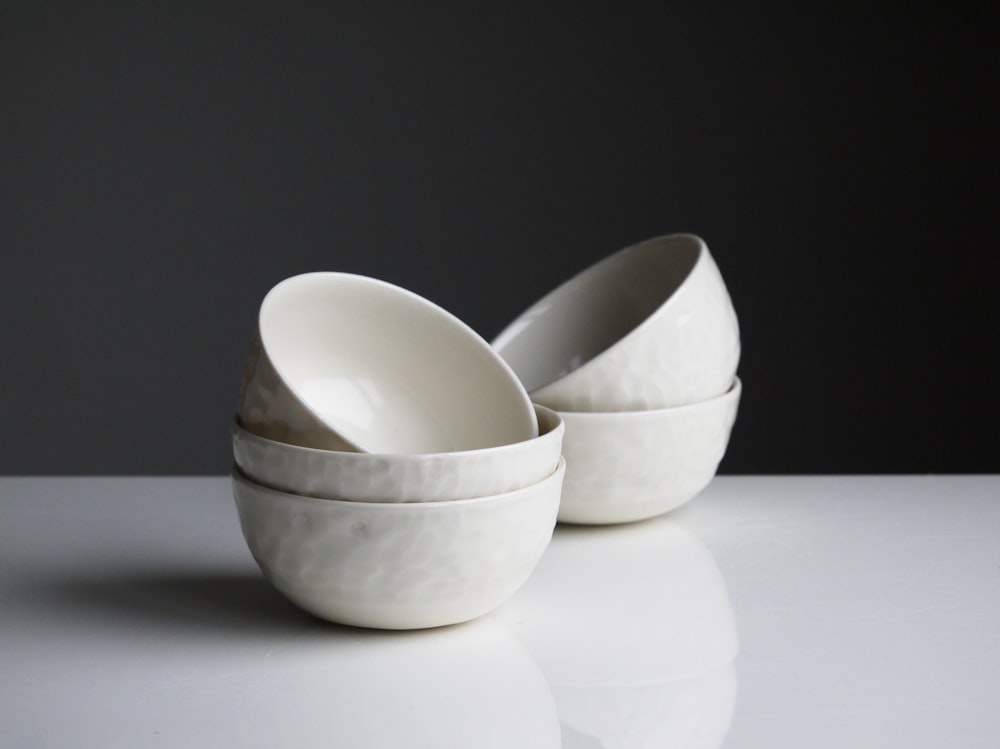 Fünf runde weiße Keramikschalen auf weißer Oberfläche