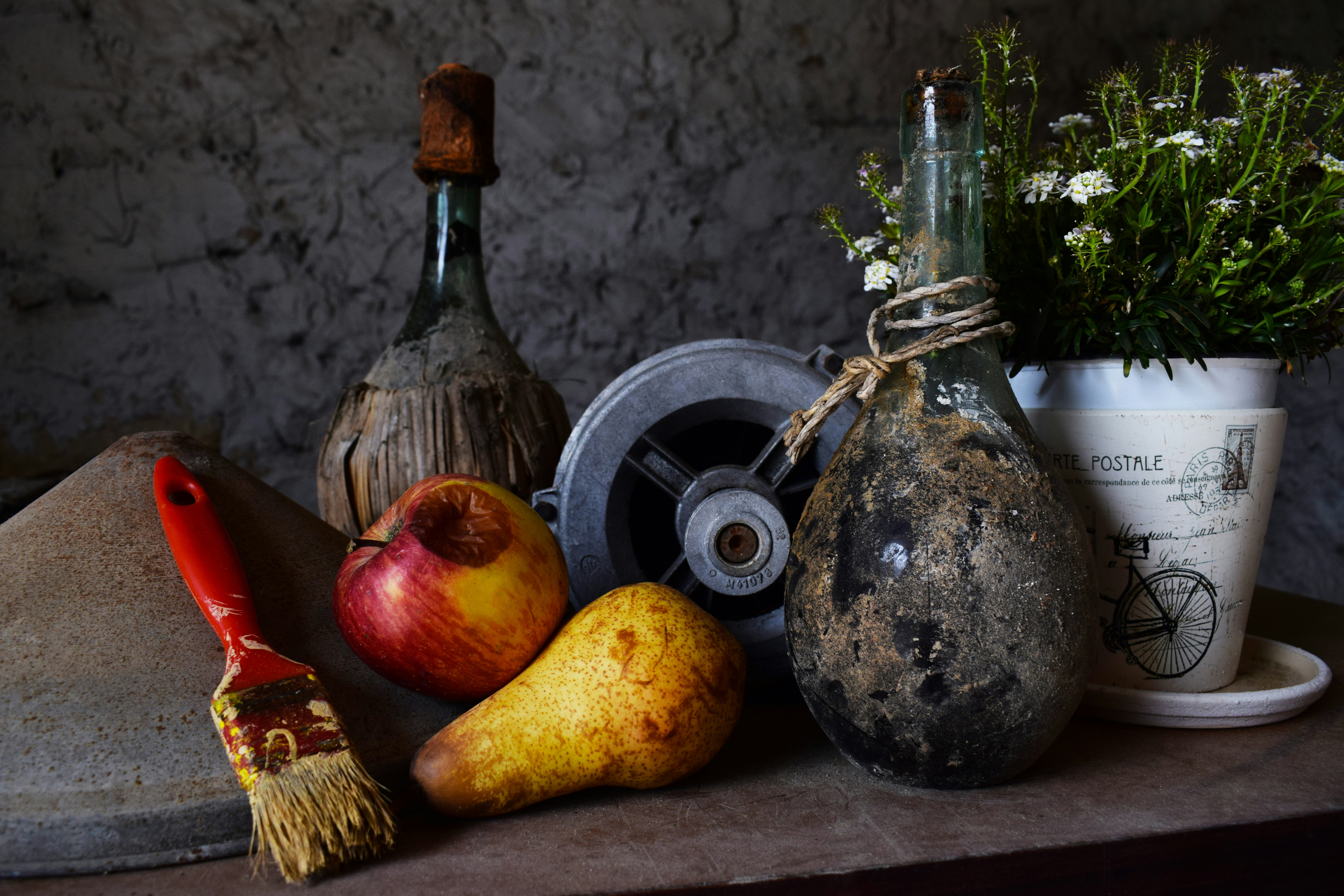 vase beside flower pot and fruits on table