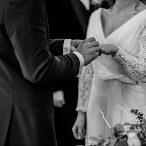 grayscale photo of man insert ring into woman during wedding ceremony