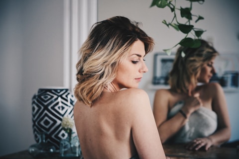 femme aux cheveux blonds se couvrant le corps avec une serviette blanche