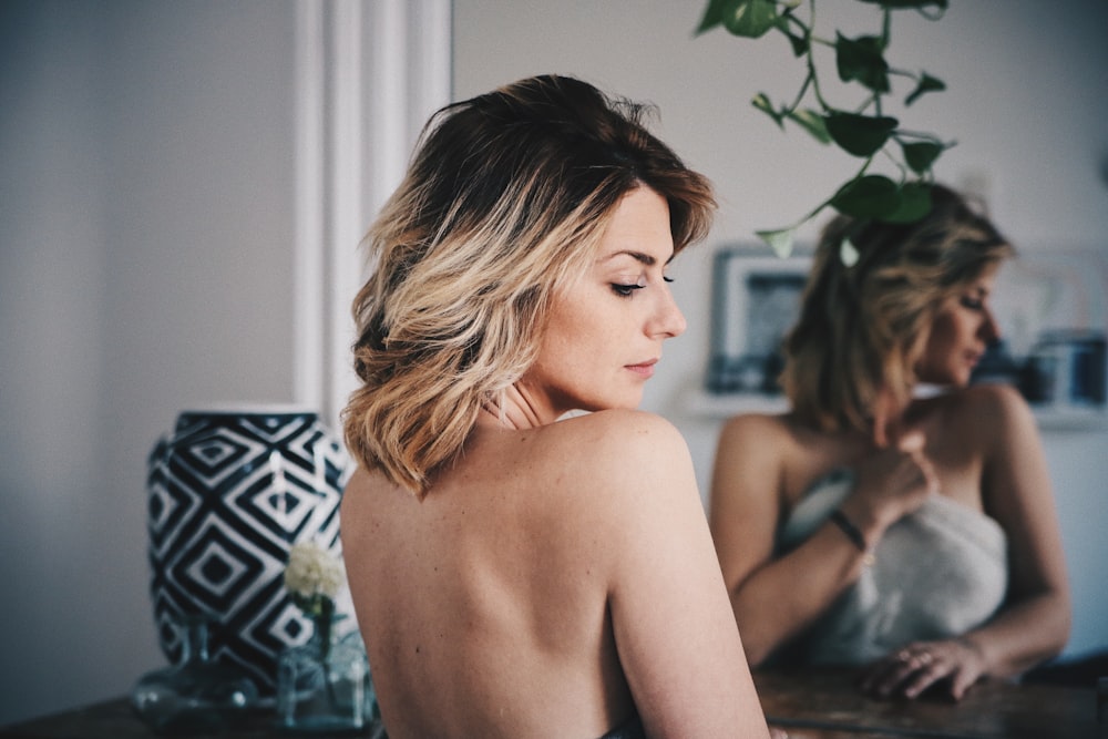 Mujer con cabello rubio cubriendo su cuerpo con toalla blanca