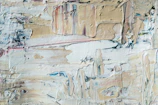 Close-up of a textured abstract painting with soft beige and gray tones.