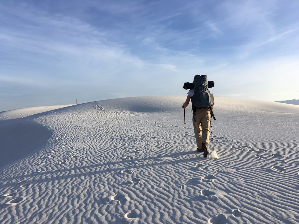 person hiking on sand dunes under white skies during daytime