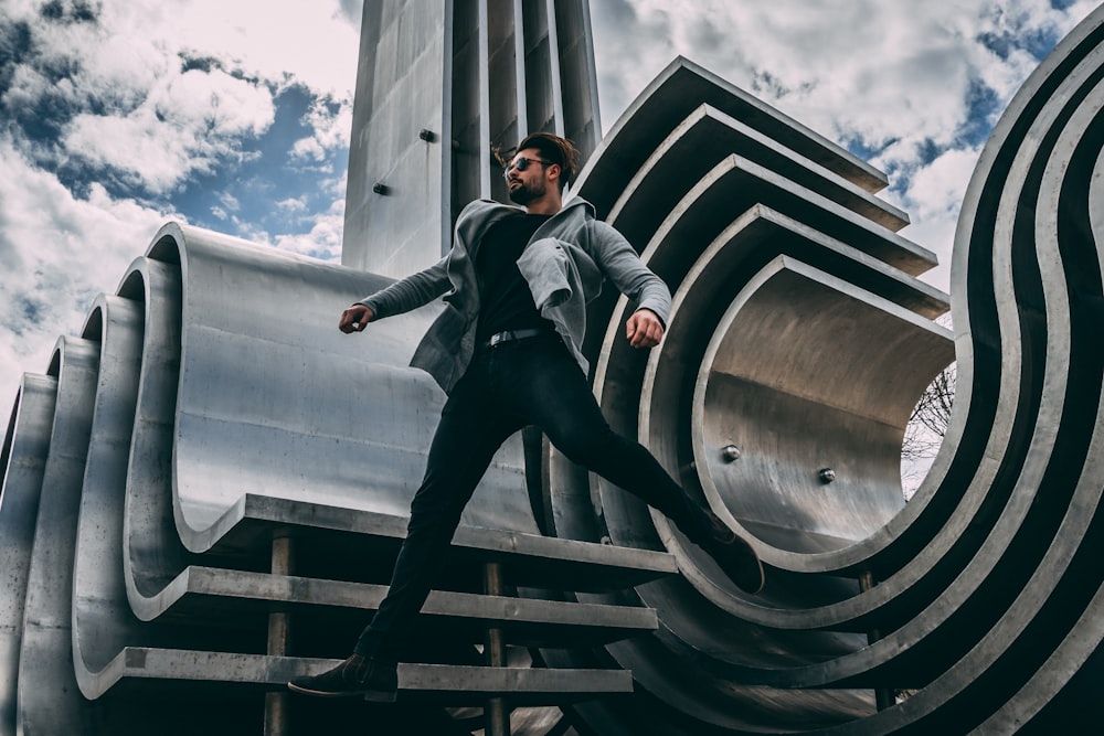 man jumping beside gray architecture