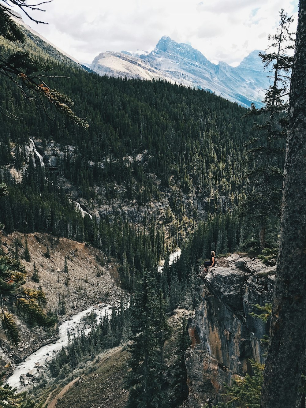 woman sitting on mountain edge during daytime