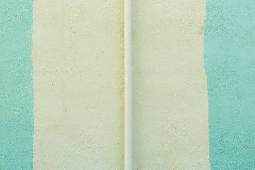 a white surfboard leaning against a blue and green wall