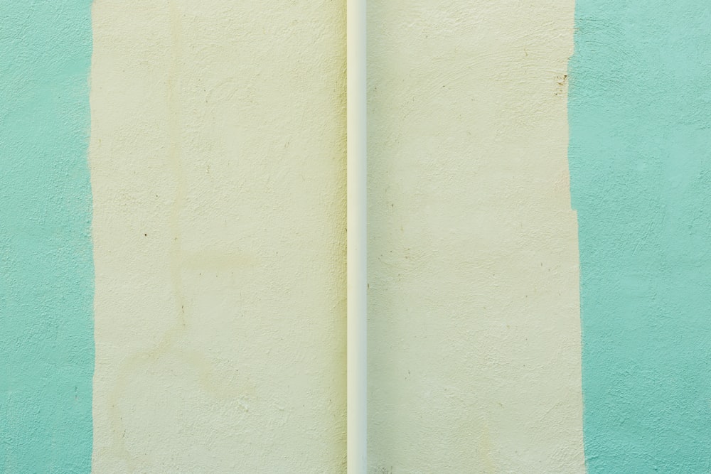 Una tabla de surf blanca apoyada contra una pared azul y verde