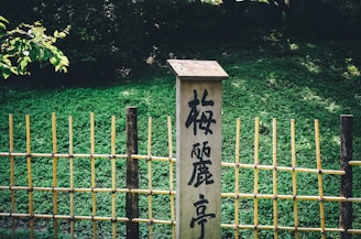 kanji text on wooden wall sign near fence