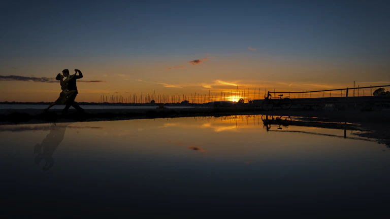 Couple dancing Brazilian zouk under string lights at sunset on the beach