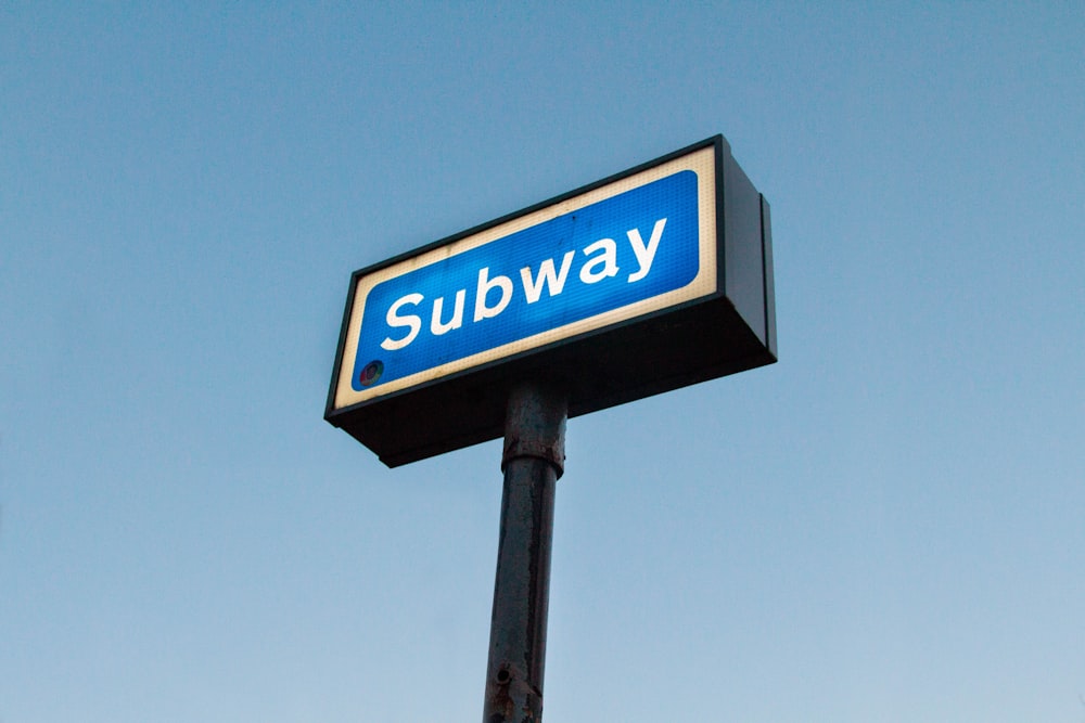 Subway signage turned on under blue sky