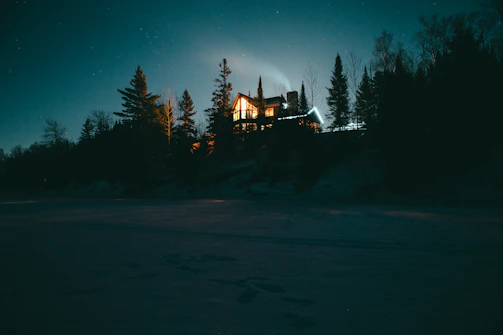 A cozy cabin illuminated by northern lights in a snowy Lapland forest