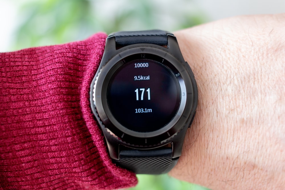 person wearing round black smartwatch