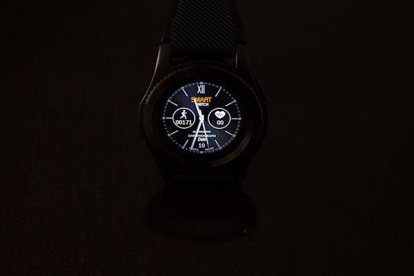 A smartwatch with a round dial is prominently displayed against a dark background. The digital screen shows various information such as time, date, heart rate, and steps. The watch face is illuminated, featuring a design with numbers, while icons indicating activity and heart monitoring are visible.