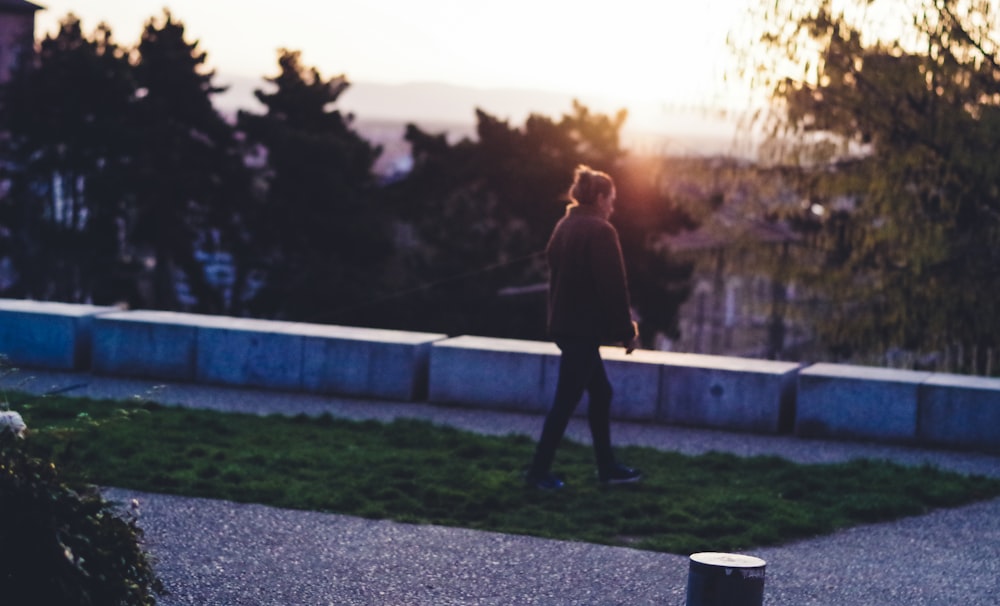 a man walking down a sidewalk next to a trash can