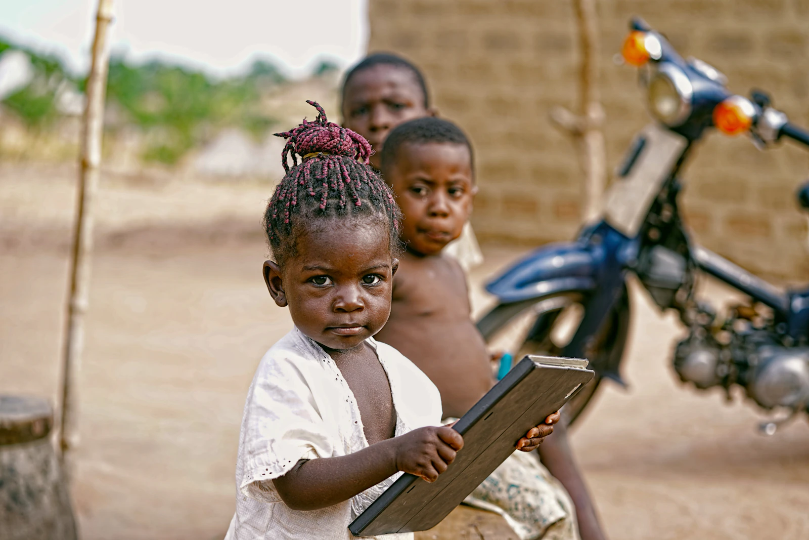 A smiling child holding a small chalkboard in class