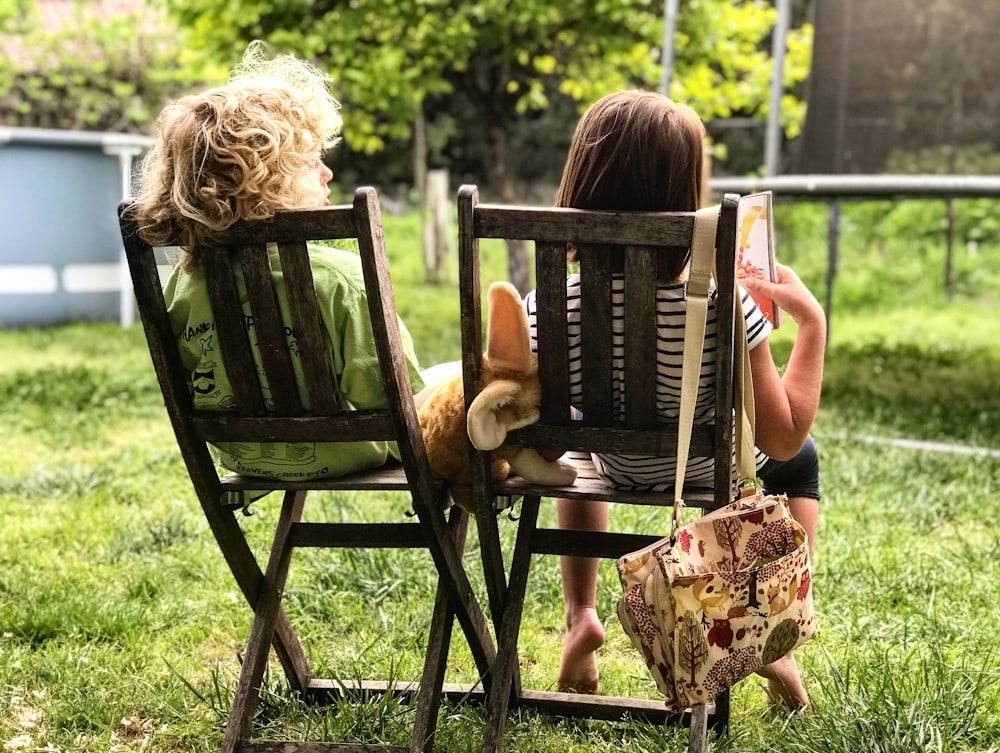 zwei Kinder sitzen auf Stühlen