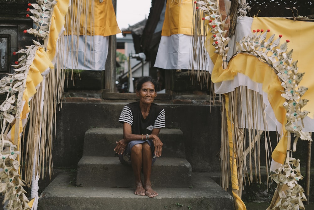 woman sitting on concrete steps between wooden fences