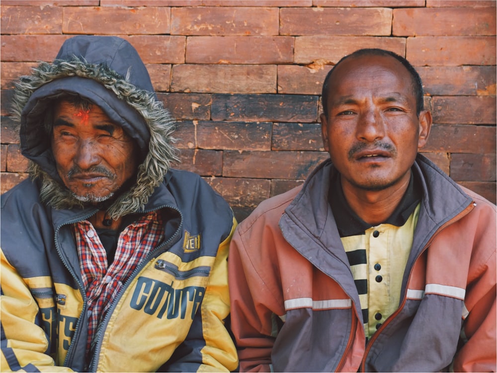 two men leaning on wall