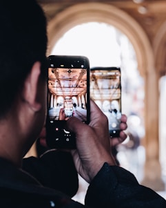 A traveler holding a smartphone displaying interactive content about a historic mosque, smiling as they explore.